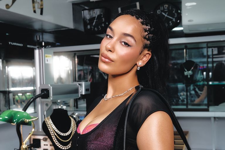 R&B singer Jorja Smith posing in a black mesh top, diamond necklace, and braided hairstyle in a jewelry shop. Photo by Rafael Salas.